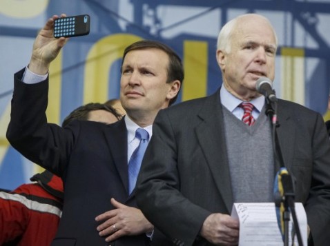 GLEB GARANICH/REUTERS -  Sen. Chris Murphy (D-Conn.), left, takes a photograph as Sen. John McCain (R-Ariz.) makes a speech to pro-European integration protesters in Kyiv.